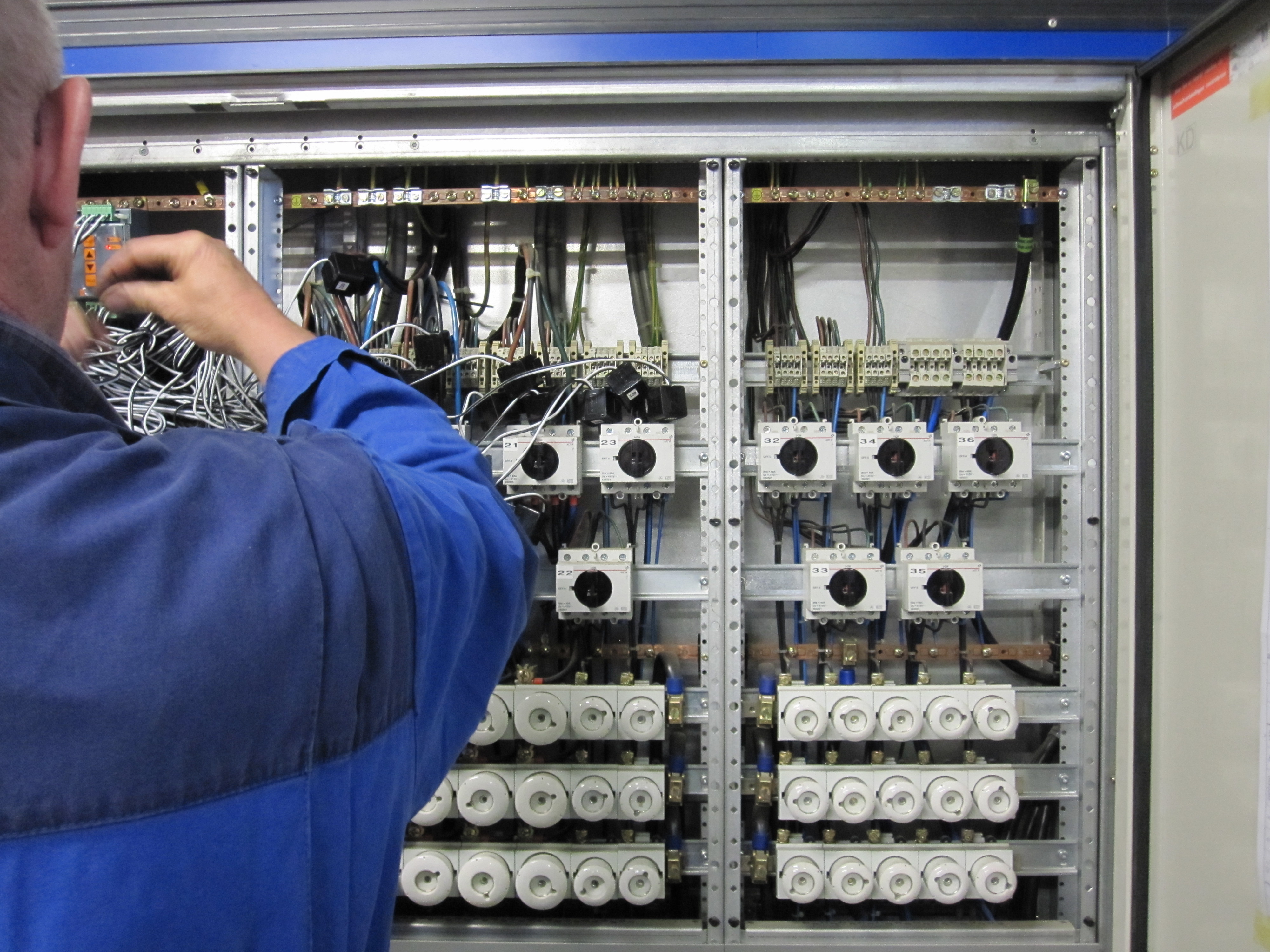 Technicus werkt aan signalen in een industriële besturingskast